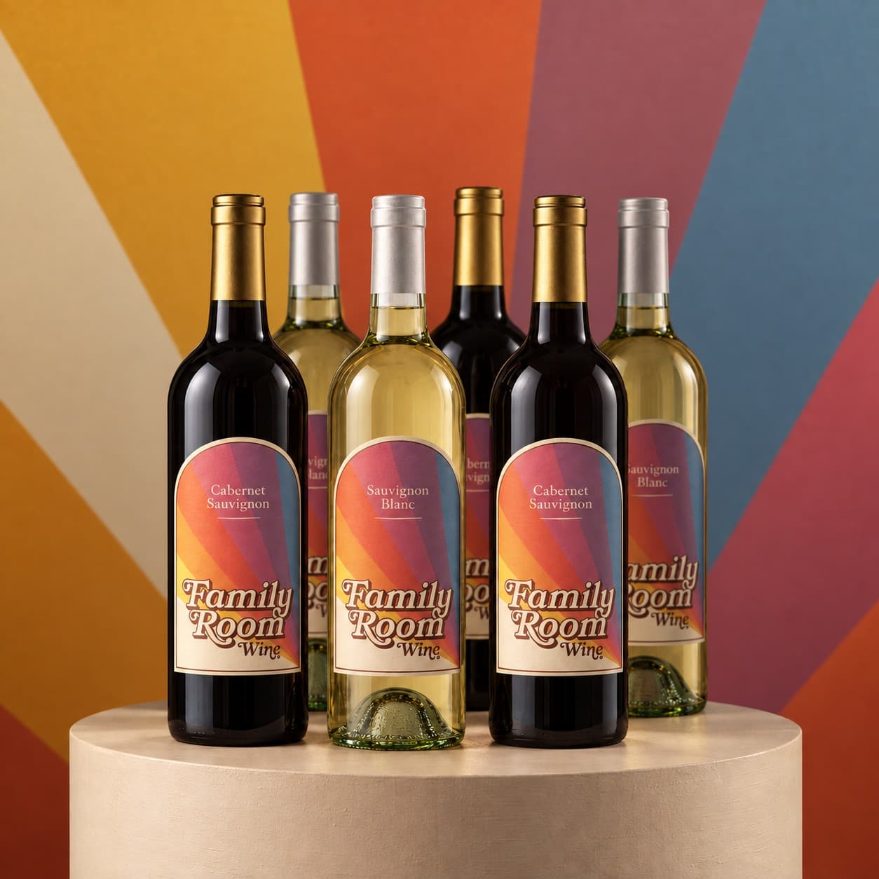 Three bottles of Family Room Cabernet Sauvignon and three of Sauvignon Blanc on a round pedestal in front of a painted sunburst wall